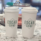 Two 20 oz. Custom Printed Recyclable Paper Cups logoed with The Edgar Grind, sits on a granite surface with a blurred macaron jar in the background. Cups printed by The Cup Store.