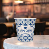10 oz. Multicolor Recyclable Paper Cup displaying "Cappucinno", on a round, marble table.