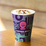 12 oz. Multicolor Recyclable Paper Cup displaying "Coffee Spot Premium", on a wooden table.