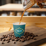 4 oz. Multicolor Recyclable Paper Cup, displaying "Coffee Time" logo, pouring espresso, on a wood board surrounded by coffee beans, on top of a wooden table.