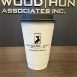 16 oz double-walled paper cup with black dome lid, black centaur logo and "Haywood Hunt & Associates Inc" text, on wooden table, black wall with silver logo