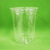 Blank 16 oz compostable plastic cup on green background.