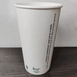 20 oz compostable paper cup showing seam, with green text printed, on grey wooden table, white wall background