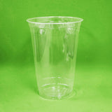 Blank 20 oz compostable plastic cup on green background.