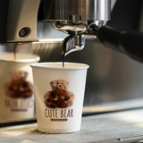 8 oz. White Multicolor Recyclable Paper Cup with "Cute Bear" logo, on a espresso machine, filling with espresso