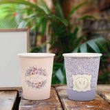 Two 8 oz. Multicolor Recyclable Paper Cup with differing designs, on a wood table, outdoors