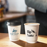 Two 8 oz double-walled paper cups with "The Brew" and "Sip Latte" print logo, filled with coffee on a table