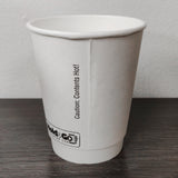 Blank white 8 oz premium double walled paper cup showing seam, on grey wooden table, white wall in background
