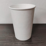 Blank white 8 oz paper cup on grey wooden table, white wall in background